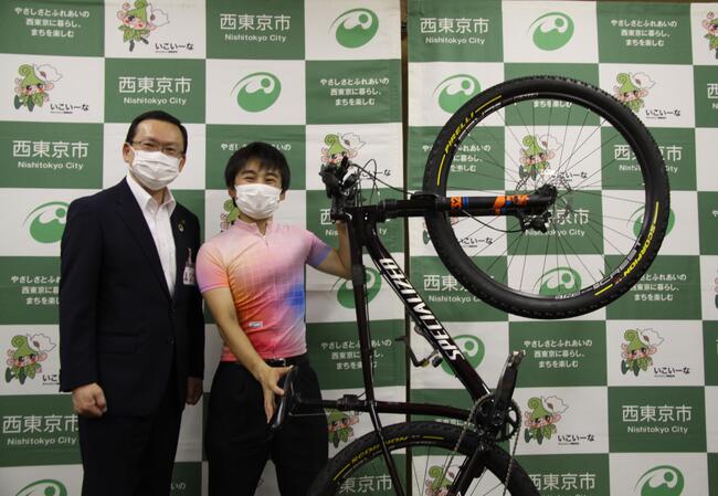 高橋選手が自転車を持ち上げながら市長と映っている写真