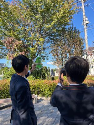 外で写真撮影をする生徒の画像