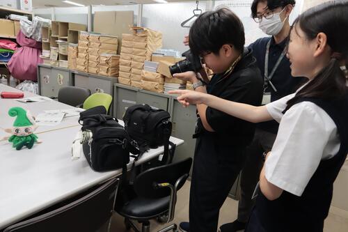 生徒2人がいこいーなのぬいぐるみを撮影している様子の画像