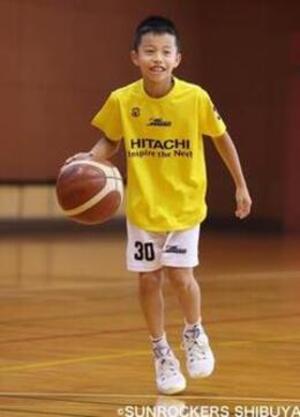 鶴岡海選手が笑顔でバスケットボールをドリブルしている写真