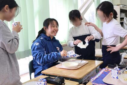 前田選手が子どもたちから、牛乳パックを広げる方法を習っている様子