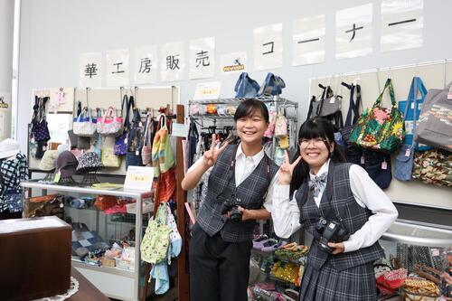 華工房販売コーナー前で映るカメラマンの二人