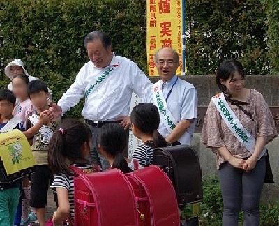 （写真：小学校校門前であいさつ運動を実施している様子）